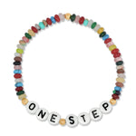 A beaded stretch bracelet featuring a variety of colorful stone beads and white letter tiles spelling 'ONE STEP' with black text, set against a plain white background.